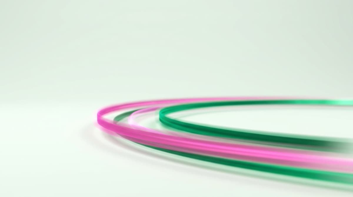 Pink and green light trails racing side by side like two funding lanes